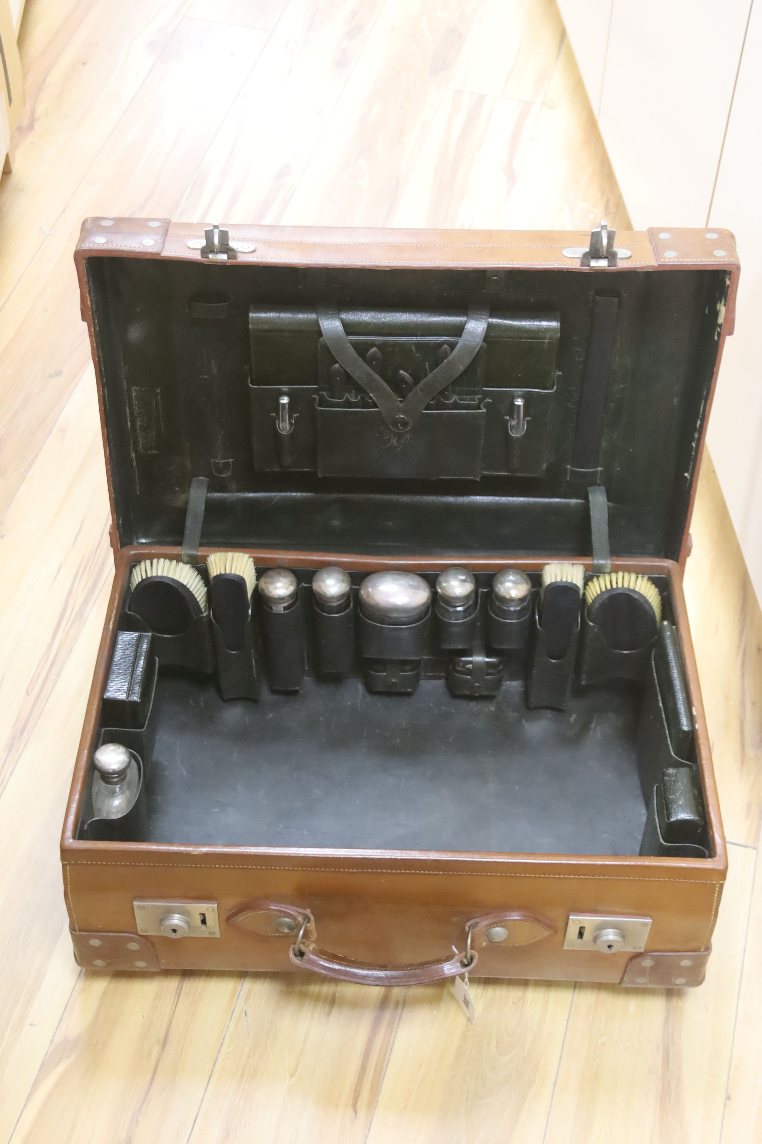 A gentleman's brown leather cased silver travelling vanity set, with silver lidded bottles interior, initialled HS